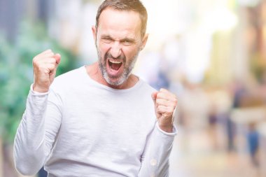 Gülümseyen ve başarı için çığlık çok mutlu ve heyecanlı kaldırdı, silah ile kazanan jest yapıyor izole arka plan üzerinde beyaz t-shirt giyen orta yaş ağarmış komuta sizde. Kutlama kavramı.