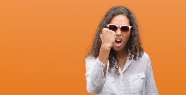 Güneş gözlüğü rahatsız ve hayal kırıklığına uğramış bağırarak öfkeyle, çılgın ve yükseltilmiş el, öfke kavramı ile diye bağıran giyen genç İspanyol kadın