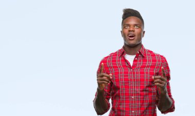 Genç Afro-Amerikan adam izole arka plan üzerinden hayran ve yukarıya bakıp parmakları ile işaret şaşırttı ve silah kaldırdı.