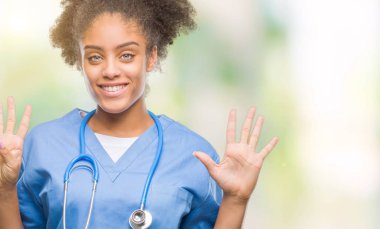 Genç afro Amerikalı doktor kadın gösterilen ve parmakları ile işaret izole arka plan üzerinde numara 9 kendinden emin ve mutlu gülümseyerek süre.