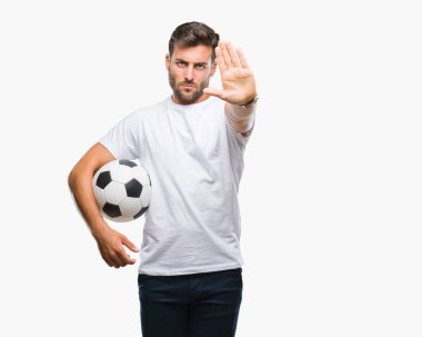 Açık eliyle dur işareti ile ciddi ve kendine güvenen ifade, savunma jest yapıyor izole arka plan üzerinde futbol futbol topu tutan genç yakışıklı adam