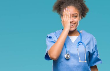 El yüz ve sürpriz duygu kendinden emin gülümseme ile tek gözüyle kapsayan izole arka plan genç afro Amerikalı doktor kadın.