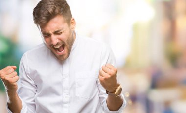 Soyutlanmış, mutlu ve heyecanlı genç bir adam kollarını kaldırmış, gülümseyen ve başarı için çığlık atan kazanan bir jest yapıyor. Kutlama konsepti.