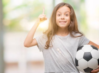 Esmer Latin kız futbol futbol topu sürpriz bir fikir ya da soru işaret parmağı gülen yüz, bir numara ile tutarak