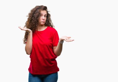 Casual göz izole arka plan clueless ve şaşkın bir ifadeyle kollar ve eller kaldırdı üzerinde giyen güzel esmer kıvırcık saçlı Genç kız. Şüphe kavramı.