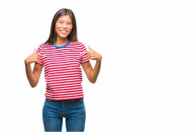 Yüzünde gülümseme ile kendinden emin görünüyorsun, kendini gururlu ve mutlu parmakları ile işaret izole arka plan üzerinde Genç Asyalı kadın.