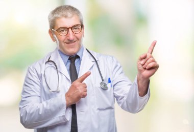 Yakışıklı kıdemli doktor erkek gülümseyen ve iki elleri ve parmakları ile tarafına işaret kamera bakarak izole arka plan üzerinde.