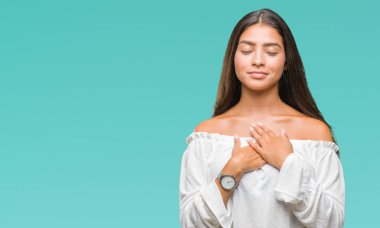 Eller genç güzel Arap kadın ile gülümseyen izole arka plan üzerinde kapalı gözler ve yüzünde minnettar jest ile göğüs üzerinde. Sağlık kavramı.