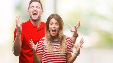 Kızgın ve çığlık kaldırdı ve kapalı gözleri heyecanlı silah ile başarı için deli kutluyor izole arka plan üzerinde aşık genç bir çift. Kazanan kavramı