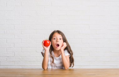 Taze domates bir sürpriz yüz, korkuyor ve heyecanlı korku ifadesi ile şok korkmuş yemek masada oturan genç İspanyol çocuk