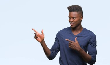 Gülümseyen ve iki elleri ve parmakları ile tarafına işaret kamera bakarak izole arka plan üzerinde genç Afro-Amerikan adam.
