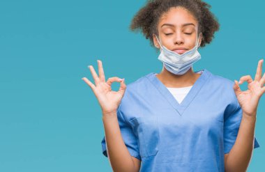 Genç afro Amerikalı doktor kadın izole arka plan üzerinde dinlenmek ve gülümseyen gözlerle parmak ile meditasyon jest yapıyor kapalı. Yoga kavramı.