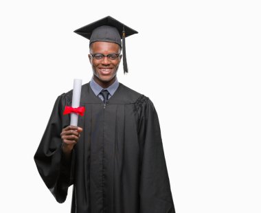 Genç Afro-Amerikan adam derecesi izole arka plan üzerinde duran ve diş gösterilen kendine güvenen bir gülümsemeyle gülümseyerek mutlu bir yüz ile tutarak mezun oldu.