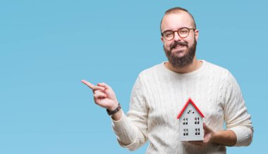 İzole evin arka plan çok mutlu el ve parmak ile tarafına işaret tutan genç beyaz gerçek durum Ajan adam