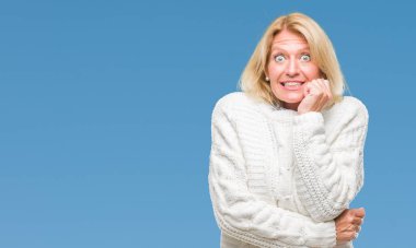 Stresli ve gergin elle çivi ısırma ağzına bakarak izole arka plan üzerinde kış kazak giyen orta yaş sarışın kadın. Anksiyete sorunu.