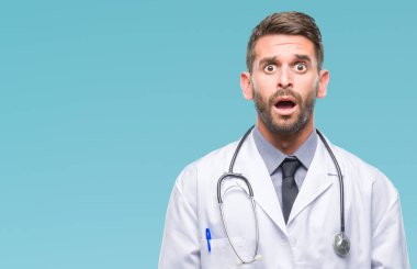 Genç yakışıklı Doktor adam izole arka plan korkuyor ve şok sürpriz ifade, korku ve heyecan yüz üzerinden.