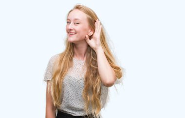 Sarışın genç kadın bir işitme söylenti ya da dedikodu için dinleme kulak üzerinde el ile gülümseyen benler gömlek giymiş. Sağırlık kavramı.