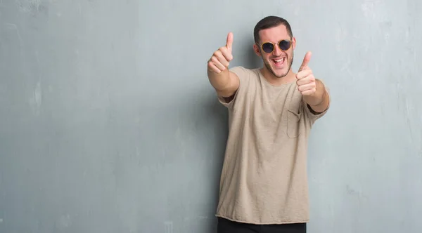 Joven Hombre Caucásico Sobre Pared Gris Grunge Usando Gafas Sol — Foto de Stock