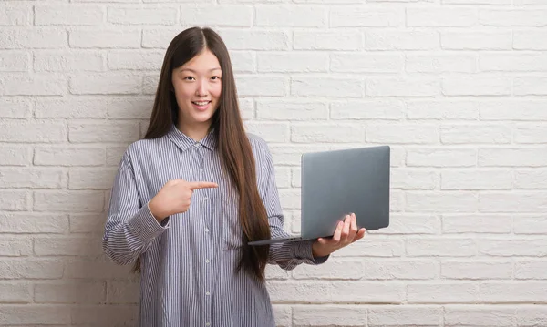 Молодая Китаянка Кирпичной Стеной Помощью Ноутбука Счастлива Указывая Рукой Пальцем — стоковое фото