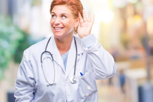 高级白种人医生妇女穿着医疗制服在孤立的背景微笑着与手耳朵听谣言或流言蜚语 耳聋概念 — 图库照片