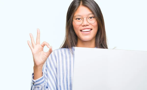 Joven Asiática Mujer Sobre Aislado Fondo Sosteniendo Blanco Banner Haciendo —  Fotos de Stock