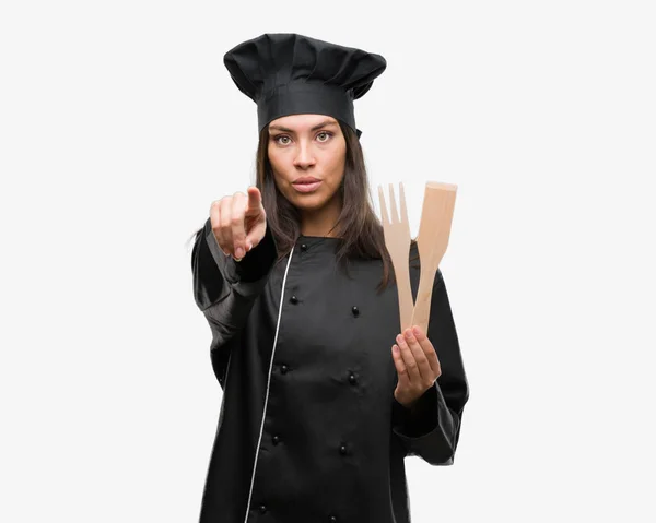 年轻的西班牙裔厨师妇女穿着厨师制服指向相机和你 正面和自信的手势从前面 — 图库照片