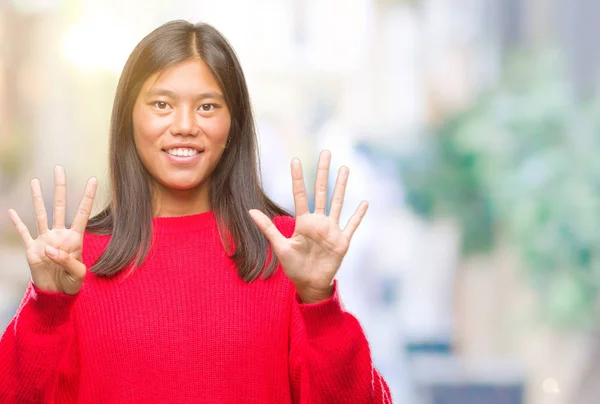 若いアジア女性着て冬セーター分離背景表示と指で上向きにナンバー ナイン自信を持って 幸せな笑みを浮かべて — ストック写真