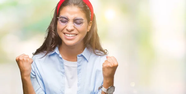 年轻美丽的阿拉伯妇女戴着太阳镜在孤立的背景下非常高兴和兴奋做赢家手势与手臂举起 微笑和尖叫的成功 庆祝概念 — 图库照片