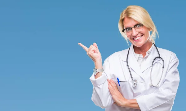 Middle age blonde doctor woman over isolated background with a big smile on face, pointing with hand and finger to the side looking at the camera.