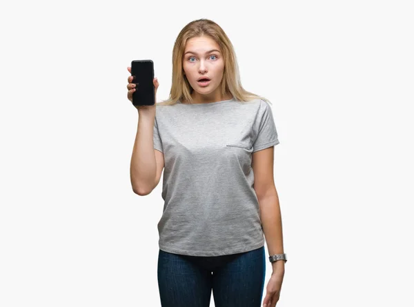 年轻的白种人妇女显示屏幕的智能手机在孤立的背景吓坏了惊讶的脸 害怕和兴奋与恐惧表达 — 图库照片