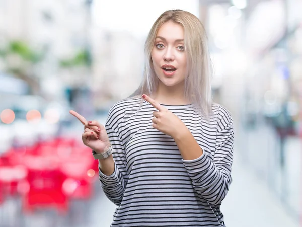 年轻的金发女人在孤立的背景下微笑着 看着相机指着两只手和手指的侧面 — 图库照片