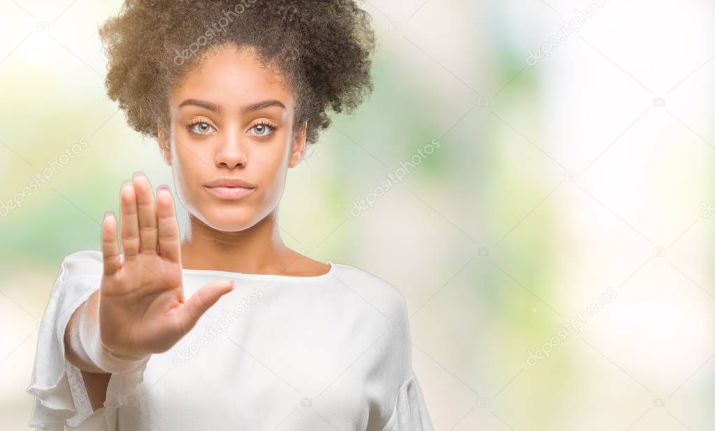 Young afro american woman over isolated background doing stop sing with palm of the hand. Warning expression with negative and serious gesture on the face.
