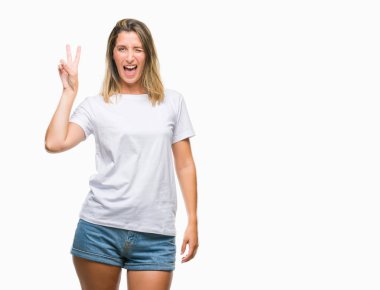 Genç güzel kadın mutlu yüz zafer işareti yaparken kameraya göz kırpıyor ile gülümseyen izole arka plan yüzünden. İki numaralı.