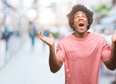 Afro Amerikalı adam deli kutluyor ve silah ile başarı için heyecanlı çığlık kaldırdı ve açık gözleri hayret izole arka plan üzerinde. Kazanan kavramı