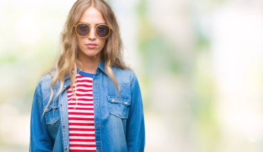 Yüzünde ciddi bir ifade ile izole arka plan üzerinde güneş gözlüğü takıyor güzel sarışın genç kadın. Basit ve doğal kameraya bakıyor.