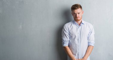 Kızgın ve korkmuş ağlıyor genç redhead iş adamı depresif gri grunge duvar ve sıkıntı, endişe içinde. Üzgün ifade.
