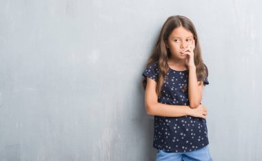 Grunge gri duvar düşünme seyir üzerinde genç İspanyol çocuk yorgun ve sıkılmış çapraz silah depresyon sorunları ile.