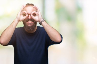 Genç beyaz hipster adam dilini, parmaklarının arasından baktığını yapışmasını dürbün gibi ok jest yapıyor izole arka plan üzerinde güneş gözlüğü takıyor. Deli ifade.