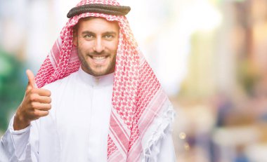 Keffiyeh hareketi el ile mutlu yaşasın yapıyor izole arka plan üzerinde giyen genç yakışıklı adam. Kameraya bakarak başarı gösteren ile ifade onaylama.