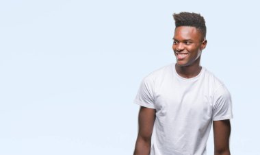 Afrikalı-Amerikalı genç uzak tarafına yüzünde, doğal ifade gülümseme ile seyir izole arka plan üzerinde. Kendine güvenen gülüyor.
