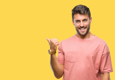 Yakışıklı delikanlı arıyor ve başparmak yanında yukarıyı mutlu yüz ile gülümseyen izole arka plan üzerinde.