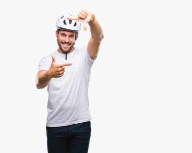 Genç yakışıklı adam elleriyle yapım çerçeve ve parmakları ile mutlu yüz gülümseyen izole arka plan üzerinde bisikletçi Güvenlik kask giyiyor. Yaratıcılık ve Fotoğrafçılık kavramı.