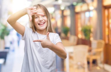 Genç güzel kız elle yapma çerçeve ve parmakları ile mutlu yüz gülümseyen izole arka plan yüzünden. Yaratıcılık ve Fotoğrafçılık kavramı.