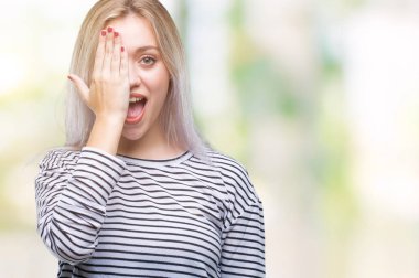 Sarışın genç kadın el yüz ve sürpriz duygu kendinden emin gülümseme ile tek gözüyle kapsayan izole arka plan üzerinde.