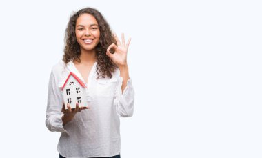 Genç İspanyol gerçek durum Aracısı kadın holding küçük ev parmak, mükemmel sembolü ile ok işareti yapıyor