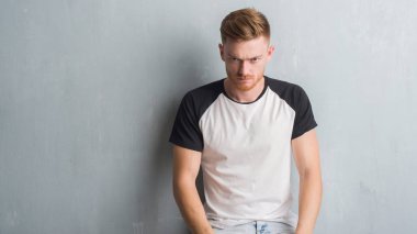 Gri grunge duvar şüpheci ve sinir, papatyanın üzgün sorun nedeniyle genç Kızıl saçlı adam. Negatif kişi.