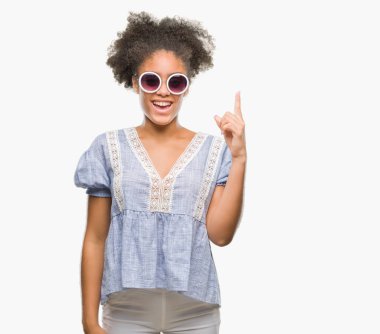 Başarılı fikirle izole arka plan işaret parmağı üzerinde gözlük takan genç afro Amerikalı kadın. Çıktıktan ve mutlu. Bir numara.