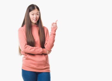 Kameraya bakarak yan el ve parmak ile işaret izole arka yüzünde, spor sweathshirt kocaman bir gülümseme ile giyen genç Çinli kadın.