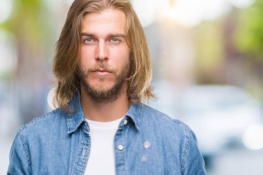 Yüzünde ciddi bir ifade ile izole arka plan üzerinde uzun saçlı Genç yakışıklı adam. Basit ve doğal kameraya bakıyor.
