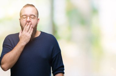 Güneş gözlüğü izole arka plan üzerinde giyen genç beyaz hipster adam el ağzıyla kapsayan yorgun esneme sıkılmış. Restless ve uyku hali.